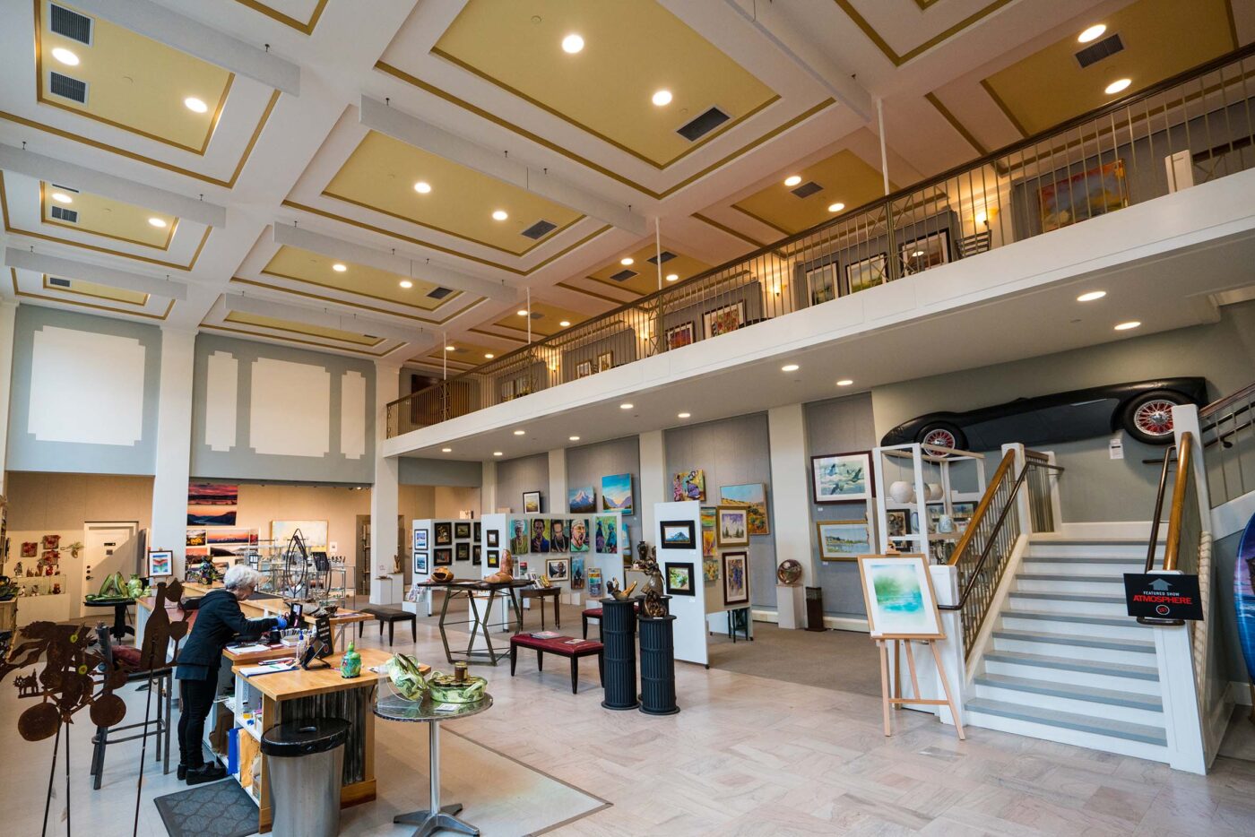 Two story gallery filled with paintings and art.